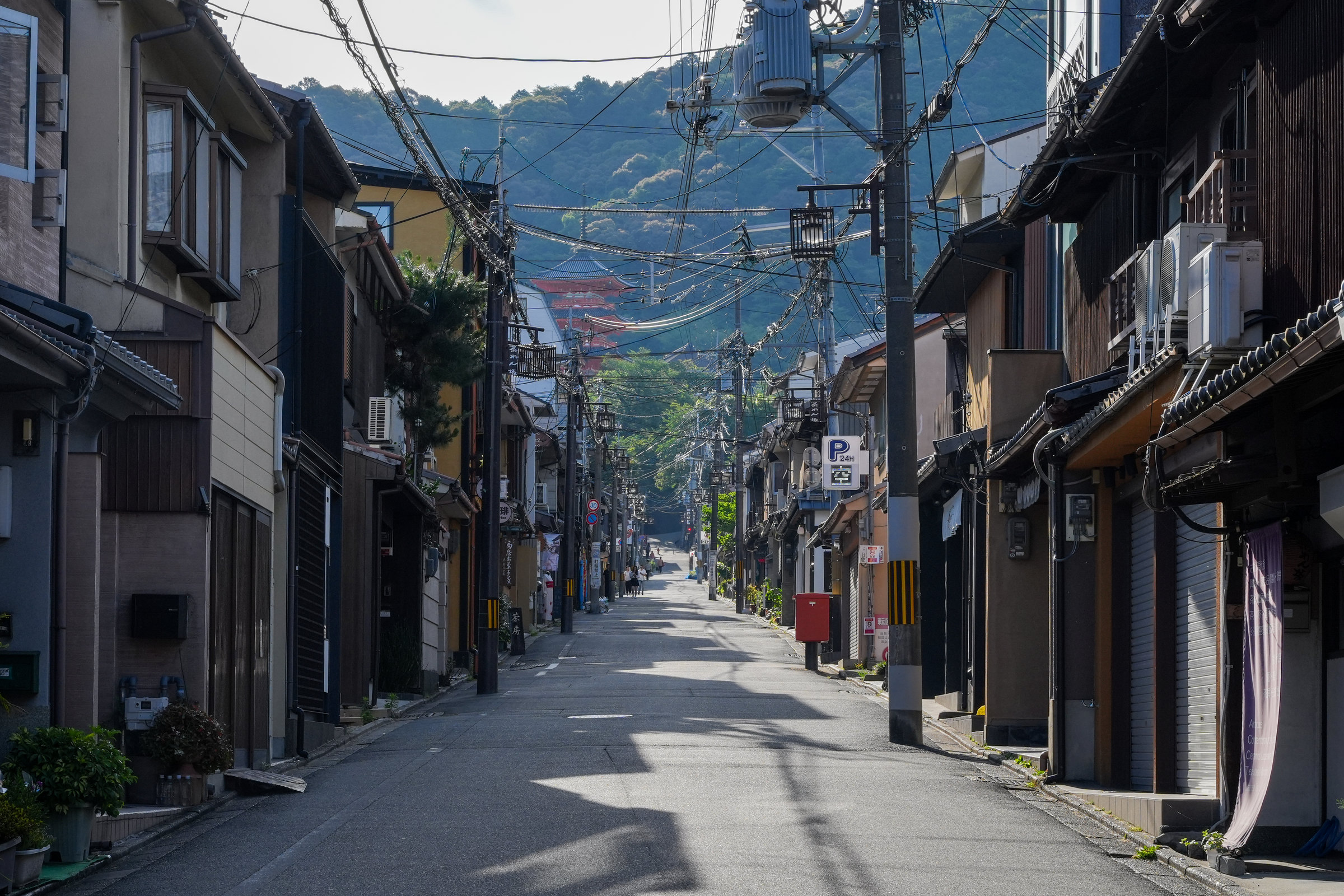 A narrow Higashiyama street leading toward the wooded hills