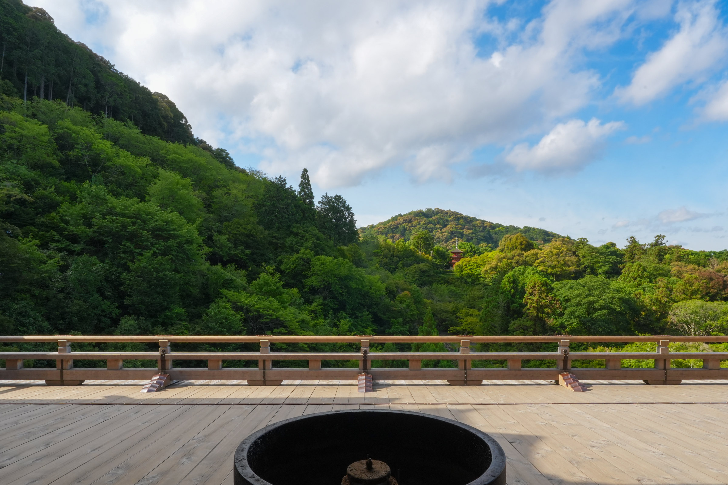 A terrace overlooking wooded hills beneath a cloudy blue sky